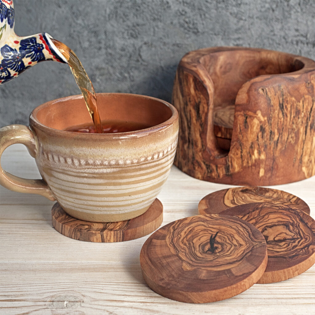 A wooden coaster next to a cup of coffee.
