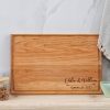A wooden cutting board with the name of the bride and groom on it.